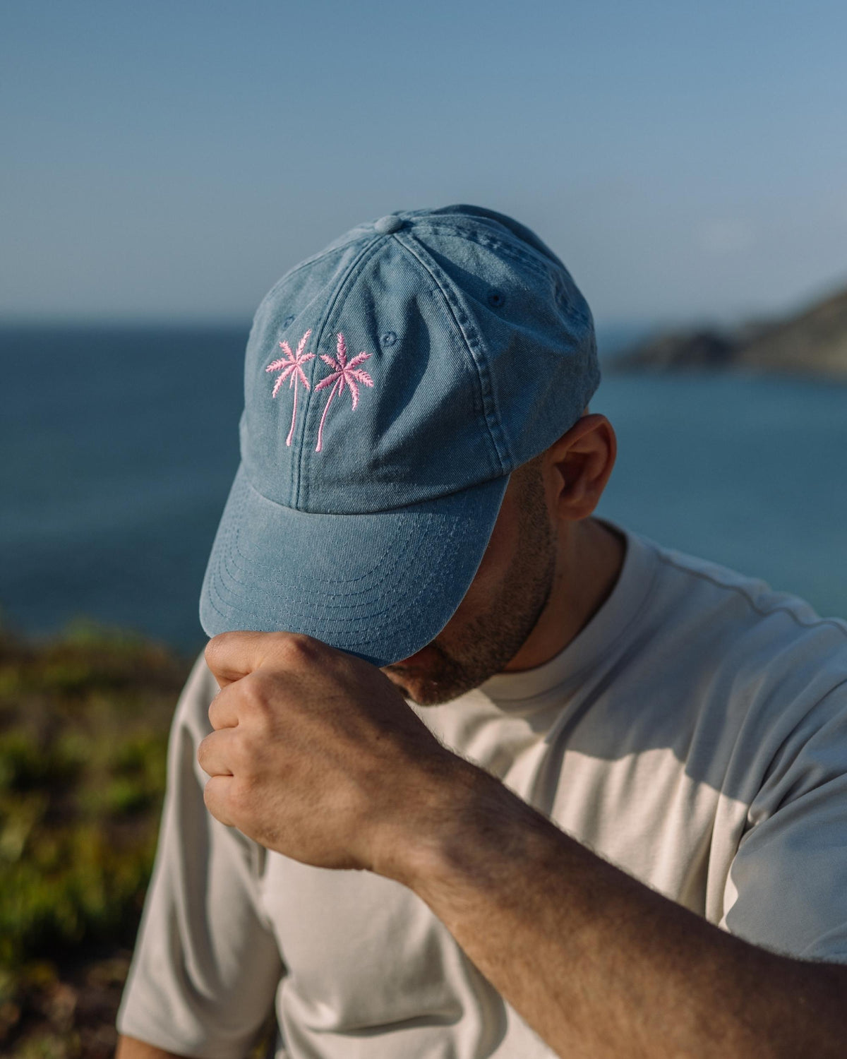 Ein Mann mit einer hellblauen Cap am Meer