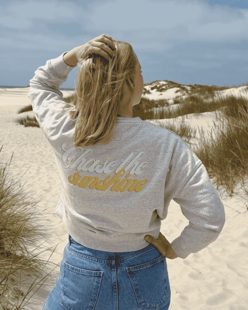 Blonde Frau mit cropped Pullover am Strand 