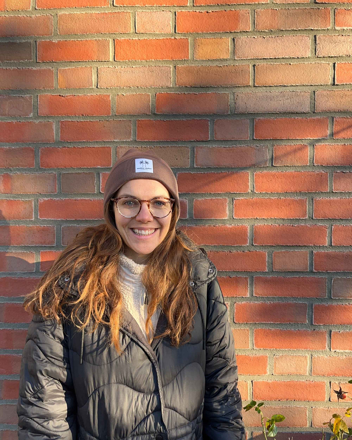 Frau mit Beanie vor Backstein Wand